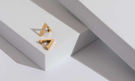 Triangle modern earrings pair on minimal geometric white background with copy space