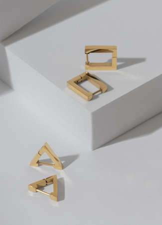 Vertical shot of two modern geometric earrings pairs on white background with copy spaceの写真素材