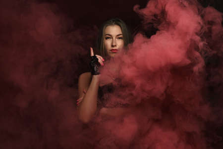 Portrait of strong woman wearing black gloves standing in red smokeの写真素材