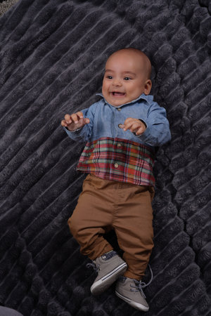 Portrait of happy baby boy in casual clothes on gray blanket with copy spaceの写真素材