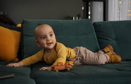 Cute baby boy in yellow shirt lying on green couchの写真素材