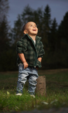 Stylish Cute toddler looking up while laughing outdoorの写真素材