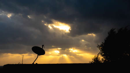 The silhouette view of the Astro plate on the roof of building with sunrise light as background in the morning. Astro is a Malaysian satellite television provider.の写真素材