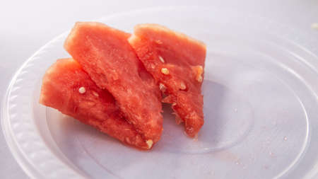The close up view of the watermelon slices on a plastic plate with white backgrounds.の写真素材