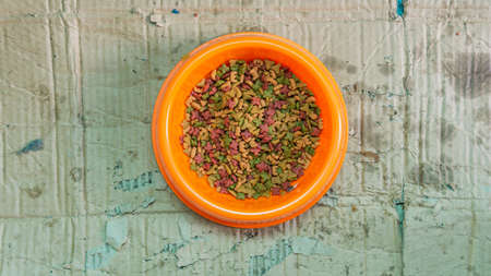 Flat lat or top view of cat diet food in a orange bowl with unfolded damages box as background.の写真素材