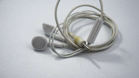 Close up view of a white tangled wired earphone on an isolated white background.