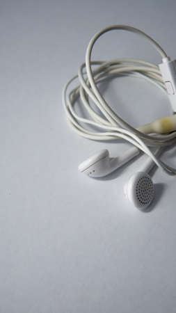 Close up view of a white tangled wired earphone on an isolated white background.