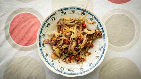 Fermented fried freshwater bream fish with fried onion or ikan pekasam in a plate on table. A traditional food in Malaysia. Marinade the fish in salt and covered it with rice powder for several weeks.の写真素材