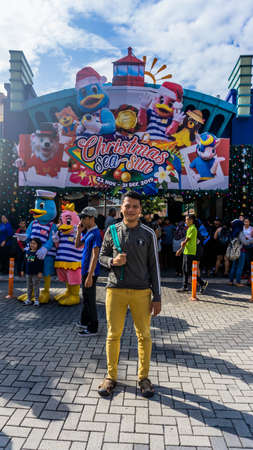 Subang Jaya, Malaysia - November 28, 2019: Unidentified man taking photo at the entrance to the Sunway Lagoon water park and theme park. Christmas season and concept. Crowd of people enter the gate.のeditorial素材