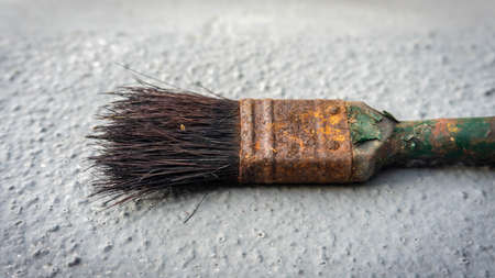 Close up view of old rusty painting brush with grey background. Paint texture peeling off from brush...