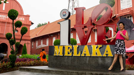 Bandar Hilir, Melaka - âJune 28, â2019 : A beautiful tourist with an umbrella taking a picture in front of "I Love Melaka" logo at Bandar Hilir during the rainy day.のeditorial素材