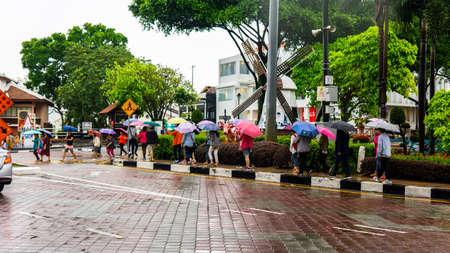 Bandar Hilir, Melaka - âJune 28, â2019 : Group of tourist walking at the side of the main road with their colorful umbrella during the rainy days in Melaka.のeditorial素材
