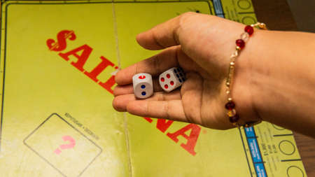 Selangor, Malaysia - July 19, 2019: Hand holding two dices to throw in to play Saidina board game, a property trading game and is a household name in Malaysia. Pay with their game fakes money to buy.のeditorial素材
