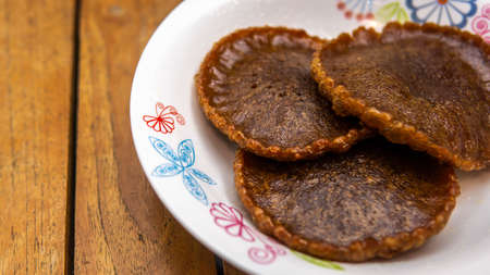 Close up view of Cucur Jawa or Cucur Topi, a traditional Malay food in a white plate on a wooden...