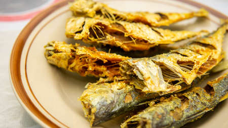 Close up view of fried mackerel fish serve in a plate on a table background. Traditional Malaysia...