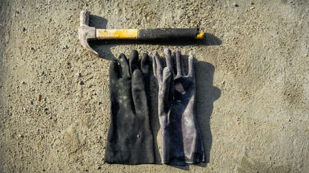 Flat lay of rusty metal hammer and construction white hand glove on grunge cement background with natural light and shadow. Labor day concept with empty copy space.の写真素材