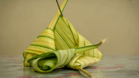 Uncooked Malay dish Ketupat Daun Palas or rice dumpling where glutinous rice is wrapped in a...
