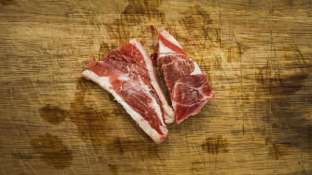 Fresh out from frozen fridge of raw beef lamb meat slices on a wooden cutting board background....