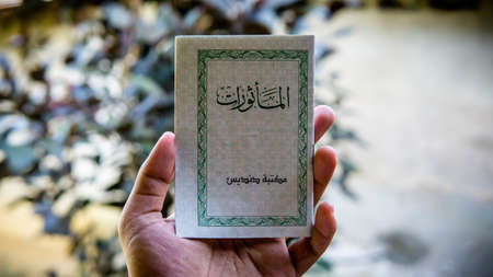Seremban, Malaysia - December 29, 2019: Hand holding a mini book written Al-Mathurat in Arabic word,...