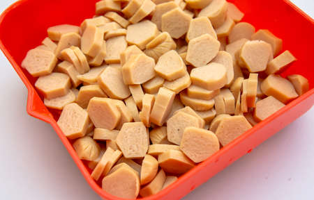 Close up view group of small slices of raw chicken sausage in a red container with isolated white background. Selective focus on foregrounds.の写真素材