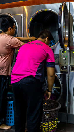 Bangi, Malaysia - July 28, 2019: Unidentified men using the cloth dryer in Mizz Launderette, a self service coin-operated washing machine and dry cloth laundry at Teras Jernang in Bangi.のeditorial素材
