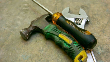 Close up view of mini hammer, adjustable wrench and screwdriver on the floor background. Some...