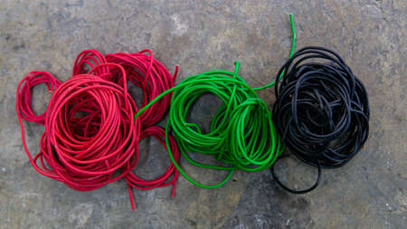 Top view of differences color, red, green and black of 1.5mm PVC insulated wire cable pure cooper scrap for recycle on the floor. It uses for electrical wiring purpose. Selective focus on foregrounds.の写真素材