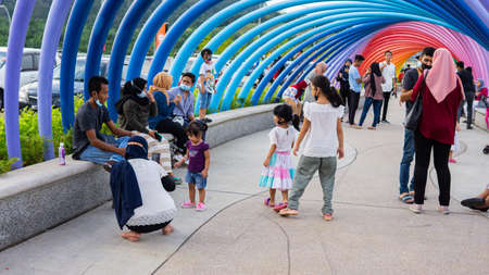 Shah Alam, Malaysia - December 25, 2020: Crowd of people visits the colorful rainbow walkway bridge at the Elmina Central Park during the holidays.のeditorial素材