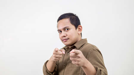 Confident and serious face expression of young Asian Malay man pointing finger at the camera and...