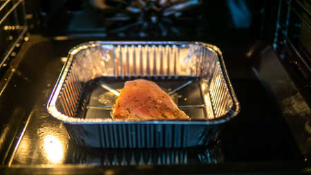 A piece of raw chicken breast meat mixed with spices in the aluminum foil box inside and oven ready for grill.の写真素材
