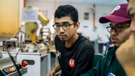 Bangi, Malaysia - October 2, 2019: Engineering students discussing and solving the task given on the automation machine system using a laptop in the laboratory. Image contain noise reduction.のeditorial素材