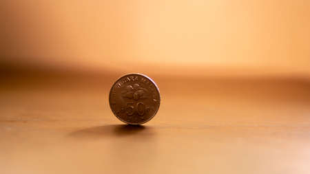 50 cent Malaysian coin on brown wooden table with light flare at background.