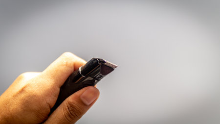 Hand holding a electric shaver for men. Leftover of men hairs and beard at the razor of shaver.