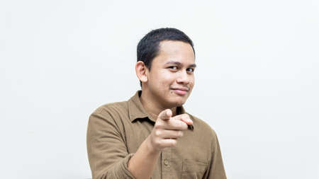 Confident and serious face expression of young Asian Malay man pointing finger at the camera and...