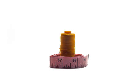 A gold sewing thread roll and sewing measuring tape on an isolated white background. Sewing tools and equipments. Cloth fashion concept.の写真素材