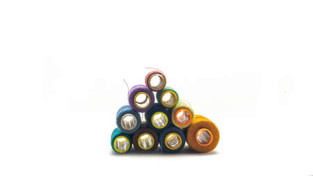 Front view pyramid of various colors of sewing thread roll on an isolated white background. Selective focus on foreground.の写真素材