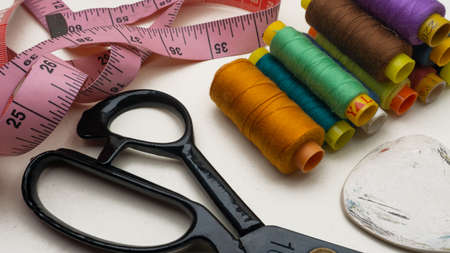 A group of various colors of sewing thread roll, fabric marker chalk, sewing measuring tape and...