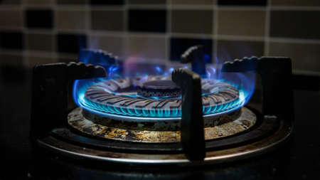 Close up view of opened fire of dirty stove. Unclean and wet gas kitchen cooktop with greasy spots, old fat stains, fry spots and oil splatters. Unsanitary conditions, a mess in the house.の写真素材