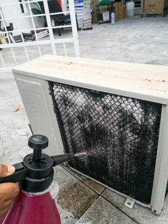 A technician spraying a chemical substance on air conditioner compressor using water dispenser pump. Overhaul cleaning service .の写真素材