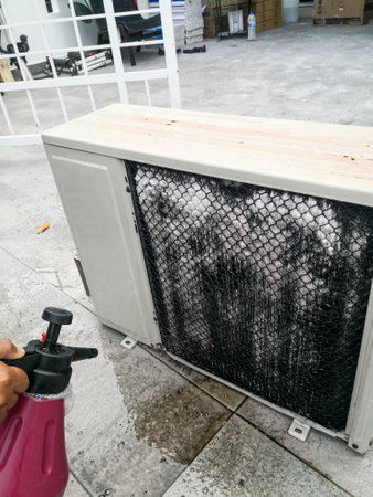 A technician spraying a chemical substance on air conditioner compressor using water dispenser pump. Overhaul cleaning service .の写真素材
