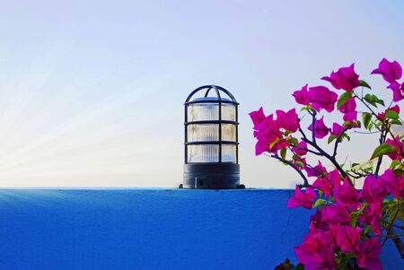 vintage glass lamp on the blue wall with purple Paper flower on clear sky backgroundの写真素材