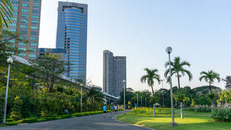 Bangkok, Thailand-April 7, 2019: People come to exercise and running in on asfalt concrete jogging track in Chatuchak public park, model building on background under blue skyのeditorial素材