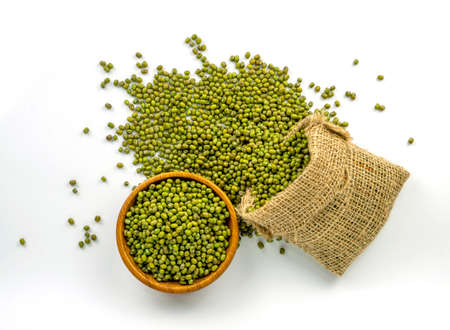 A pile of Mung bean known as green beans in a brown sack and wooden bowl, top view on white...