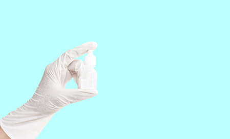 A person hand wearing white medication rubber glove and holding a white bottle of liquid medicine, isolated die cut on  backgroundの写真素材