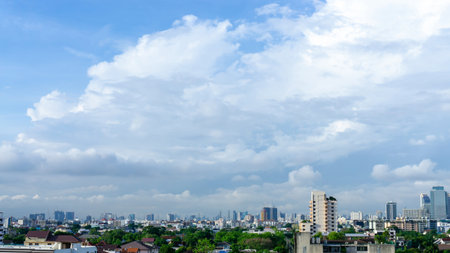 Beautiful white fluffy cloud formation on vivid blue sky in a sunny day above big city, view from rooftop a part of Bangkok in Thailandの写真素材