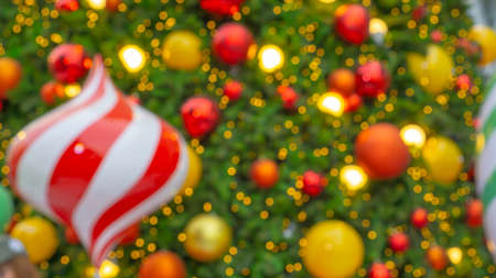 Bokeh photo, Decorative of Chistmas tree with fake red and white lollipop candy, golden yellow and, red bolls on green leaves of pine tree, decoration seasonal for celebrate Merry Chistmas and happy new yearの写真素材