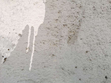 White color on grey color rough texture concrete wall skin with random small hole pattern cement plaster on its surfaceの写真素材