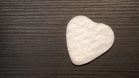White heart shape paper cutted for surprise valentines day present on black wooden background, top view photoの写真素材
