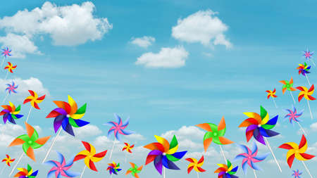 Colorful blades turbines flying on white fluffy cloud, paper rainbow windmill drawing illustration die cut on pastel blue sky photo backgroundの写真素材