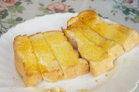 Grilled bread sliced with yellow butter topping in a white ceramic dish on the table for a breakfast